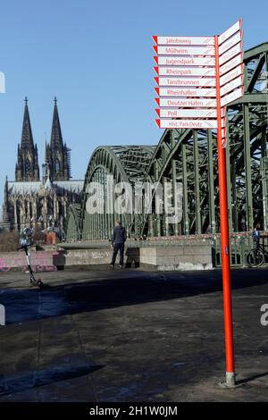 Fahrradwegweiser am Rheinufer, hinter der Hohezollernbrücke und der Dom, Deutschland, Nordrhein-Westfalen, Köln-Deutz