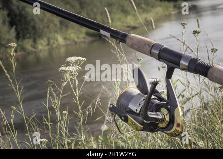 Am Ufer des schönen Flusses über dem Wasserzubringer installiert - Englisch Angelgerät für den Fang von Fischen bequem mit der Rute und der Haspel. Stockfoto