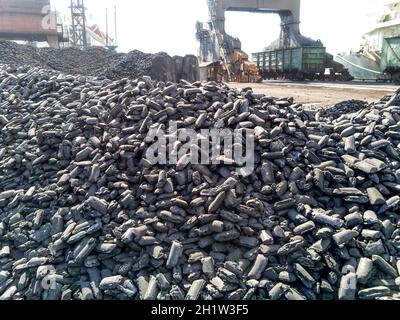 Stapel von rohem Stahl Briketts. Haufen Kohle anthrazit im Hafen. Hafen Kräne für Kohle zu laden. Stockfoto