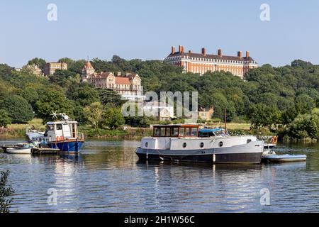 Die Themse vom Thames Towpath im Stadtteil Richmond aus, mit dem Petersham Hotel und den Royal Star & Garter Home Buildings in der Ferne. Stockfoto