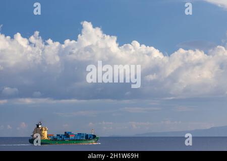 Frachtschiff in der Nähe Capo Peloro Leuchtturm in Punta del Faro an der Straße von Messina, nordöstlichste Landzunge von Sizilien, Italien Stockfoto