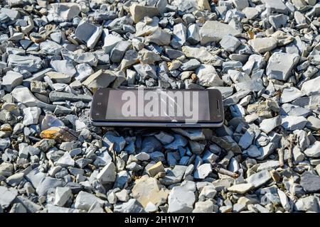 Frustriert Telefon auf den Felsen. Glas zerbrochen auf Felsen auf einem Smartphone. Smartphone fiel und stürzte ab. Stockfoto