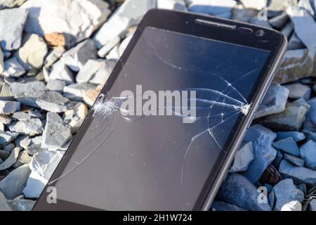 Frustriert Telefon auf den Felsen. Glas zerbrochen auf Felsen auf einem Smartphone. Smartphone fiel und stürzte ab. Stockfoto