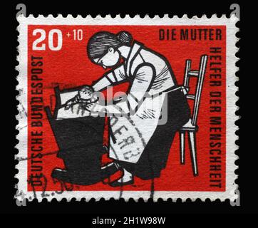 Briefmarke gedruckt in Deutschland, zeigt Mutter mit Babywiege, um 1956 Stockfoto