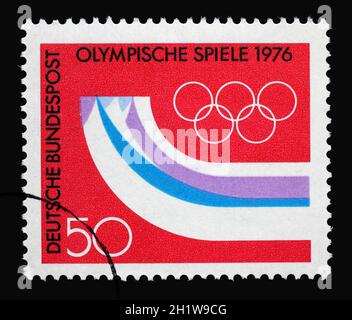 Eine in Deutschland gedruckte Marke zeigt stilisierte Berge in Form von Läufern, 12. Olympischen Winterspielen, Innsbruck, Österreich, um 1976 Stockfoto