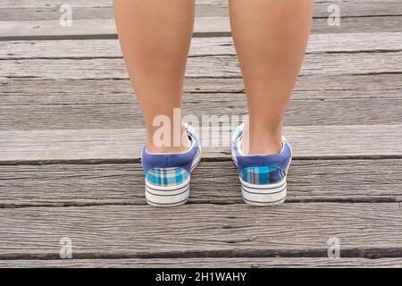 Mädchen mit Canvas Sneaker stehen auf der Holzbrücke. Stockfoto