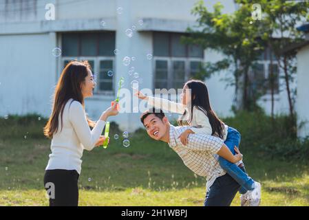 Happy Asian Lifestyle Familie Mutter, Vater und kleine niedliche Mädchen Kind Spaß zusammen und genießen im Freien spielen Seifenblasen in der Garde Stockfoto