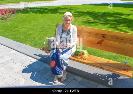 Weibliche Hände halten leere Handtasche nach dem Einkaufen im Park. Ältere Frau zeigt ihre leere Brieftasche. Insolvenz. Das Konzept der Armut. Stockfoto