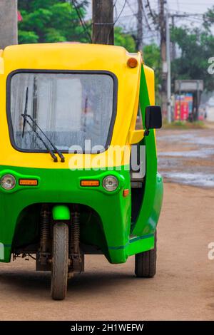 Grün und gelb umweltfreundliche elektronische Tuk Tuk Fahrzeug Auto Rikscha in Luang Prabang Laos Asien. Stockfoto