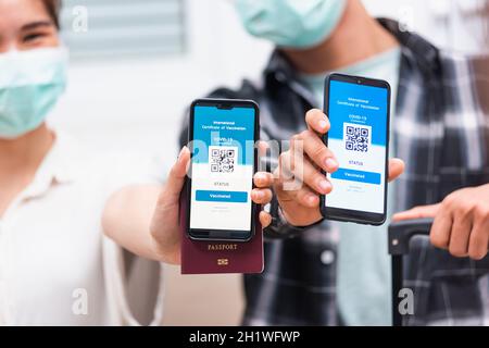 Asiatische junge Paar Frau und Mann bereit zu reisen zeigen digitale Impfstoff Gesundheit Pass Zertifikat App auf dem Smartphone-Bildschirm während Coronavirus pande Stockfoto