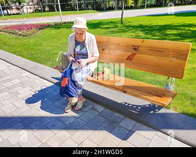 Weibliche Hände halten leere Handtasche nach dem Einkaufen im Park. Ältere Frau zeigt ihre leere Brieftasche. Insolvenz. Das Konzept der Armut. Stockfoto