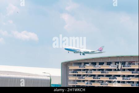 SAMUT PRAKAN, THAILAND-15. MAI 2021 : China Airlines Frachtflugzeug fliegt über dem mehrstöckigen Parkhaus des Flughafens Suvarnabhumi in Thailand. Luft l Stockfoto