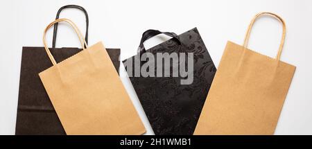 Einkaufstaschen Kraftpapier braun und schwarz auf weißem Hintergrund, Draufsicht, Black Friday Sale, Urlaub Geschenk-Konzept. Stockfoto