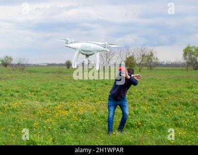 Ein Mann verbirgt sich von einer Kollision mit einer Drohne. Quadrocopter fliegt die Person. Stockfoto