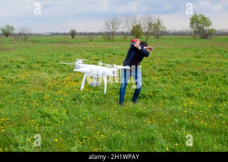 Ein Mann verbirgt sich von einer Kollision mit einer Drohne. Quadrocopter fliegt die Person. Stockfoto