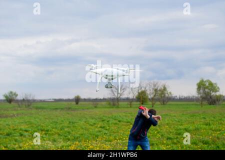 Ein Mann verbirgt sich von einer Kollision mit einer Drohne. Quadrocopter fliegt die Person. Stockfoto