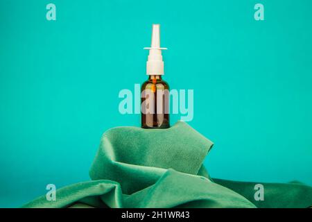 Nasenspray-Glas auf Stoff stehen auf blauem Hintergrund Stockfoto