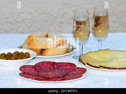 Eine Auswahl an spanischen Tapas wie Manchego Käse, grünen Oliven und Salami mit zwei Gläser fino Sherry, Andalusien, Spanien. Stockfoto