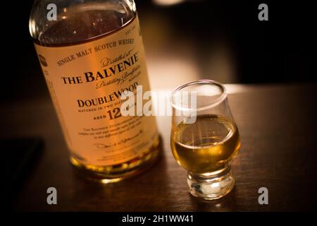 Bukarest, Rumänien - 5. August 2021: Illustrative redaktionelle Abbildung einer Balvenie Scotch Whisky-Flasche mit Single Malt-Malt neben einem Glas auf der Theke in einem Pub. Stockfoto