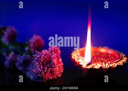 Handgefertigter Umweltfreundlicher Ton Diya Deep Dia Leuchtet Mit Blumen Auf Blauem Hintergrund. Thema Des Indischen Festivals Für Diwali Pooja, Navratri, Dussehra Puja, Stockfoto