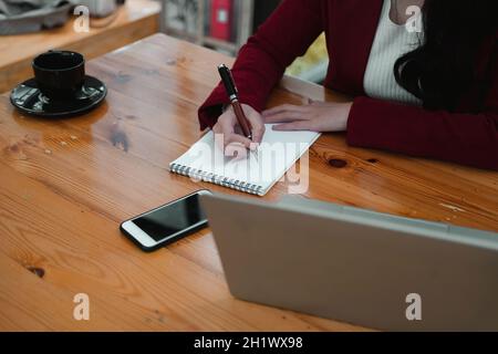 Remote-Teilnehmer. Fokussierte junge indische Dame, die Kopfhörer trägt, üben im Fernlernen der englischen Sprache Schreibtest vor pc-Bildschirm. Hinduistische Frau Stockfoto