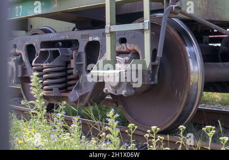 Das Fahrwerk des Schlittens mit Rädern und Federn. Personenzug, Güterzug. Industrielle Eisenbahnräder aus nächster Nähe Stockfoto