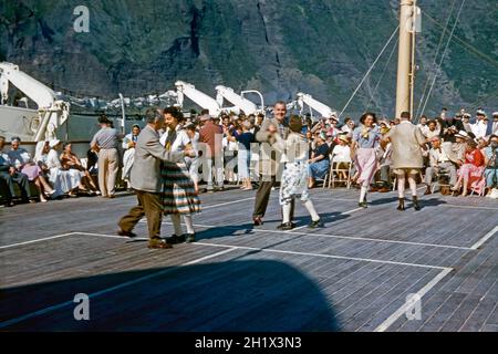 Tanzen an Deck auf einem Kreuzschiff Mitte der 1950er Jahre. Das Schiff war der Ozeandampfer TSS Maasdam der Holland America Line (HAL). Es scheint, als ob eine gute Zeit von Tänzern und Zuschauern zu haben ist. TSS Maasdam startete 1952 zu ihrer Jungfernfahrt von Rotterdam nach New York. Obwohl die TSS Maasdam mit einem zweiklassigen Layout gebaut wurde, war sie für ihre Zeit ein revolutionäres Schiff, da sie im Wesentlichen als Touristenklasse-Liner gebaut wurde – ein Vintage-Foto aus den 1950er Jahren. Stockfoto