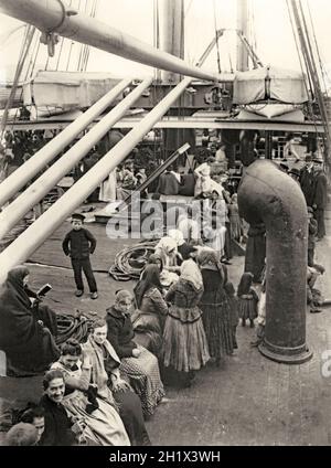 Die transatlantischen europäischen Emigranten, die sich auf dem Weg nach Nordamerika befinden, bekommen in den frühen 1900er Jahren frische Luft auf dem Deck der SS Pretoria der Hamburg-America Line. SS Pretoria war ein transatlantisches Linienschiff, das 1897 in Deutschland gestartet wurde und den größten Teil ihrer Karriere bei Hamburg America Line (HAPAG) verbrachte. Ihre Jungfernfahrt machte sie 1898. Die reguläre Strecke nach Pretoria war Hamburg – Cherbourg – Plymouth – New York. Das Schiff hatte die erste, zweite und dritte (Steuerklasse) Klasse. Die Lenkerbefahrung war eine sehr unbequeme Erfahrung mit Passagieren unter überfüllten und beengten Bedingungen – ein altes Foto aus dem 19. Jahrhundert. Stockfoto