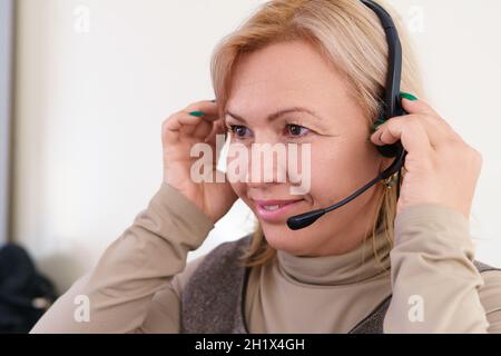 Nahaufnahme einer lächelnden Frau mittleren Alters mit Headset. Stockfoto