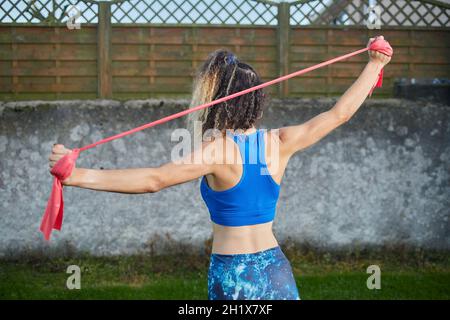 20s Frau Durchführung von Übungen mit elastischen Bändern. Sport-Konzept Stockfoto