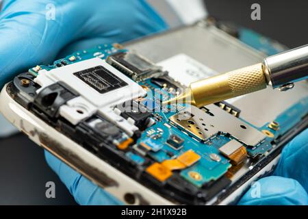Techniker repariert die Innenseite der Festplatte mit einem Lötkolben. Integrated Circuit. Das Konzept von Daten, Hardware, Techniker und Technik. Stockfoto