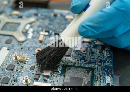 Der Techniker verwendet eine Bürste und eine Luftgebläse, um Staub im Leiterplattencomputer zu reinigen. Reparatur Upgrade und Wartung Technologie. Stockfoto