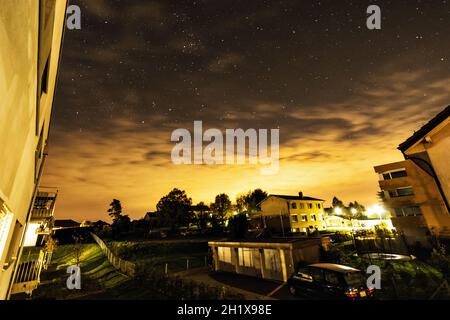 Nacht mit Sternen und Wolken mit Gebäuden im Hintergrund in Cossonay, Schweiz Stockfoto