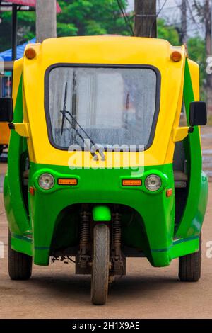 Grün und gelb umweltfreundliche elektronische Tuk Tuk Fahrzeug Auto Rikscha in Luang Prabang Laos Asien. Stockfoto