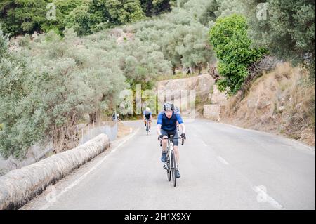 Seniorradler mit zwei unkenntlichen Radfahrern im Hintergrund auf einem Bergpass Stockfoto