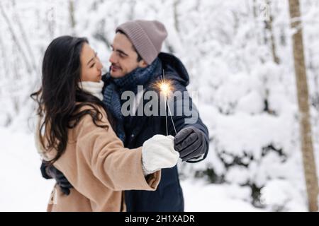 Liebespaar in Schneestreiben küssen und Sparklers halten. Paar in der Winternatur. Pärchen Feiern Stockfoto