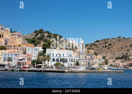 SYMI, Griechenland - 03. JUNI 2021. Der Hafen von Symi Stadt mit den Bezirken Chorio und Gialos ist einer der schönsten und romantischsten in der ganzen A Stockfoto