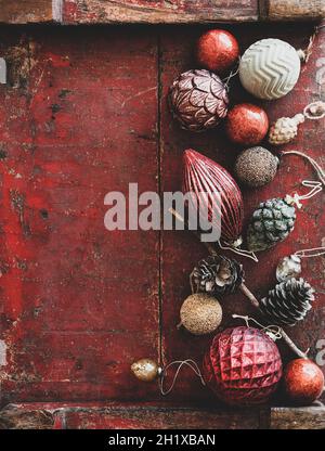 Weihnachtsdekoration Spielzeug und Kugeln über dunkelroten rustikalen Holzhintergrund Stockfoto