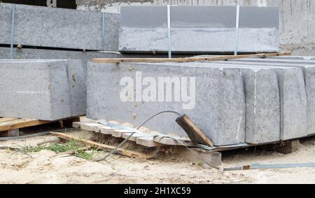 Facettierte Granitkanten auf einer Palette. Glatte Feinsteinzeugprodukte auf der Baustelle. Randstein, ein Stapel von Beton Bordsteinplatten vorbereitet f Stockfoto