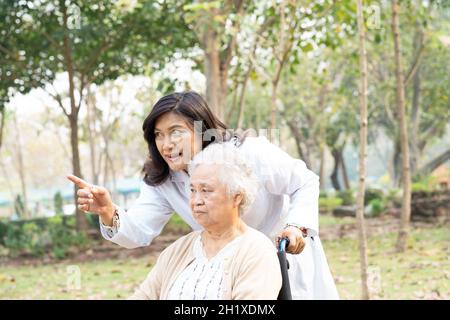 Arzt Hilfe und Pflege asiatische ältere Frau Dame sitzt auf Rollstuhl im Park. Stockfoto