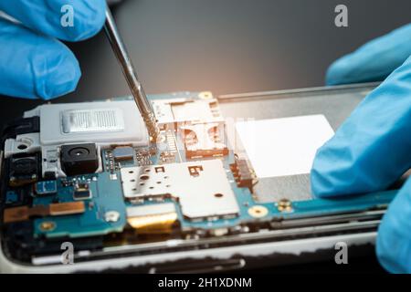 Techniker repariert die Innenseite der Festplatte mit einem Lötkolben. Integrated Circuit. Das Konzept von Daten, Hardware, Techniker und Technik. Stockfoto