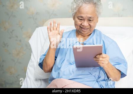 Asiatische ältere oder ältere alte Dame, die digitale Tablets für Videoanruf verwendet; Konzept der sozialen Distanzierung. Stockfoto