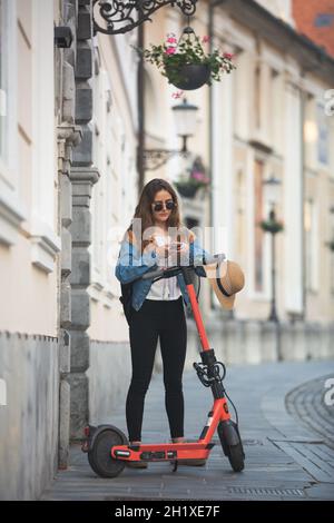 Elektromobilität. Reisende entsperren einen E-Scooter über eine App auf ihrem Smartphone. Reisende, die die Altstadt mit umweltfreundlichen elektrischen SCO erkunden Stockfoto