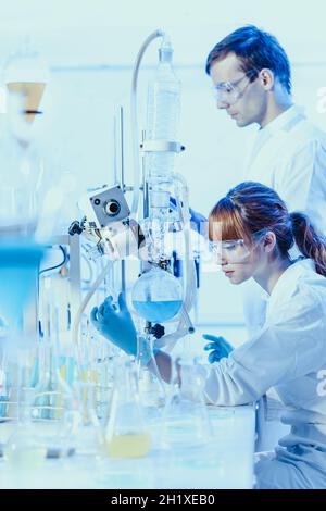 Chemische Forschung im Labor. Attraktive junge promovierte Forscher, Studenten und ihr Doktorvater Wissenschaftler beobachten die blaue Anzeige Farbe sh Stockfoto