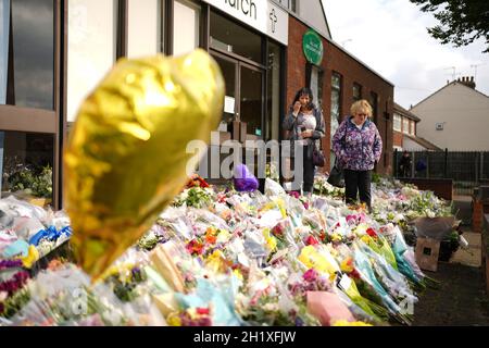 Die Menschen sehen sich die Blumengebete an, die vor der Methodistischen Kirche von Belfairs in Leigh-on-Sea, Essex, zurückgelassen wurden, wo der konservative Abgeordnete Sir David Amess am Freitag getötet wurde. Bilddatum: Dienstag, 19. Oktober 2021. Stockfoto