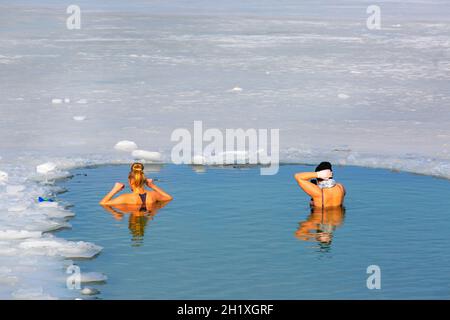 Krakau, Polen - 20. Februar 2021 : zwei junge Frauen tauchten in kaltem Wasser, während sie im Winter in einem Eisloch eines gefrorenen Kryspinow-Sees schwammen Stockfoto