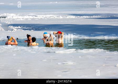 Krakau, Polen - 20. Februar 2021 : eine Gruppe von Menschen tauchte in kaltem Wasser auf, während sie im Winter in einem Eisloch eines gefrorenen Kryspinow-Sees schwammen Stockfoto