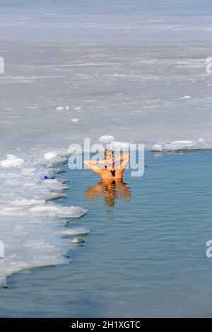 Krakau, Polen - 20. Februar 2021 : Junge Frauen tauchten im Winter in kaltem Wasser, während sie in einem Eisloch eines gefrorenen Kryspinow-Sees schwammen Stockfoto