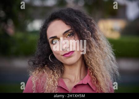 Preise blonde Frau mit lockigem Haar sitzt auf dem Stamm eines Baumes in schönen rosa Pin-up-Kleid. Stockfoto