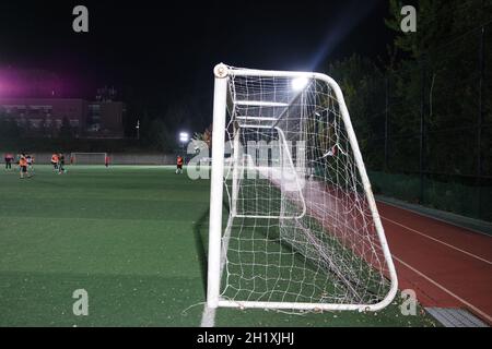 Nachtansicht eines Fußballtor-Netzes unter Flutlicht. Nahaufnahme des Tornetzes auf einem Fußballplatz Stockfoto